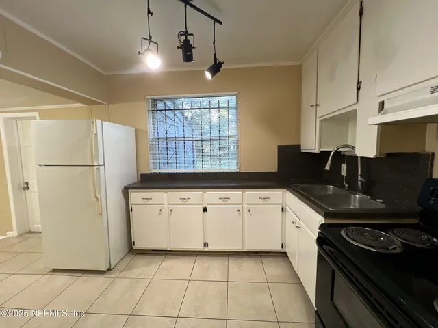 a kitchen with a refrigerator a sink and wooden cabinets