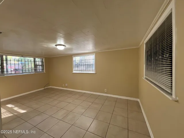 a view of an empty room with window and chandelier fan