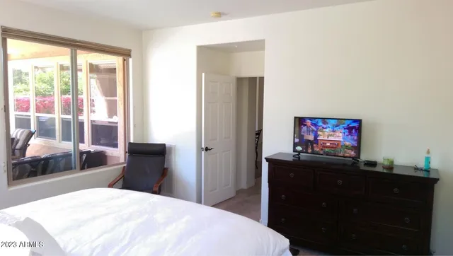 a bedroom with a bed and a flat tv screen on dresser