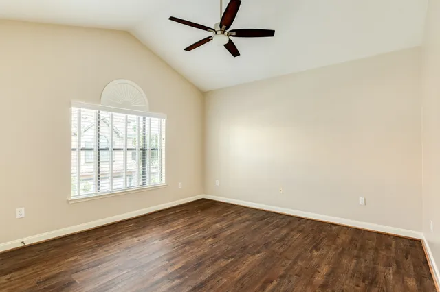 an empty room with wooden floor ceiling fan and windows