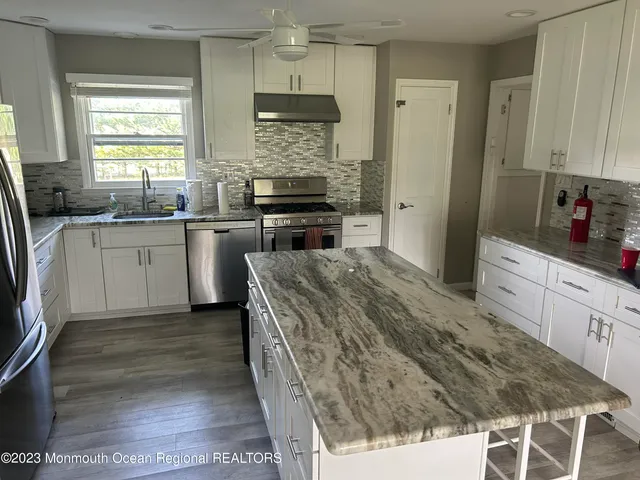 a kitchen with stainless steel appliances granite countertop a stove a sink and a refrigerator