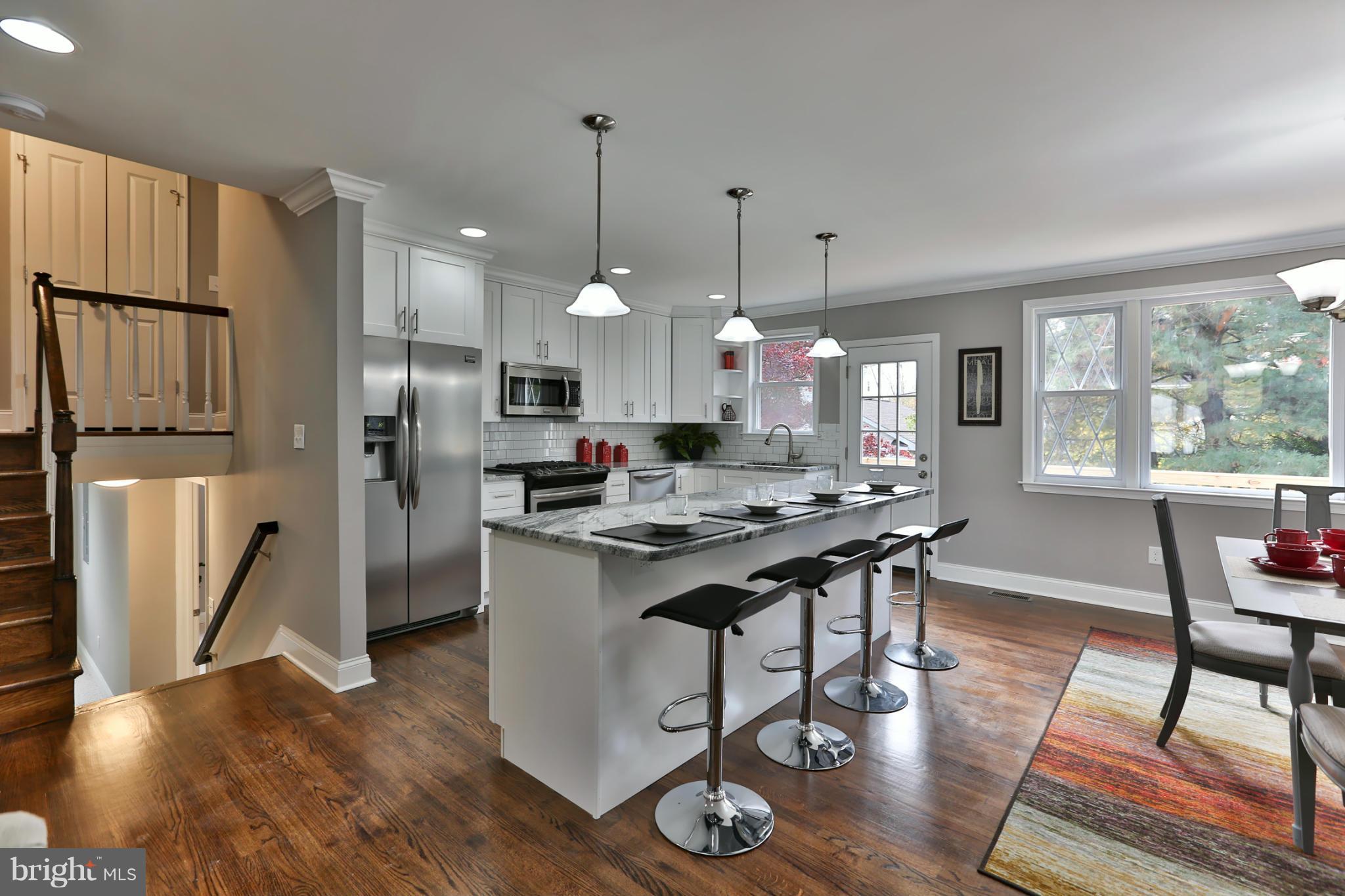 203 Hollen Road Baltimore, MD 21212 - Photo 9 of 30 a kitchen with stainless steel appliances granite countertop a stove refrigerator a dining table and chairs with wooden floor