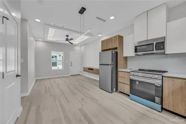 a kitchen with stainless steel appliances granite countertop a refrigerator a stove oven a sink dishwasher and white cabinets with wooden floor