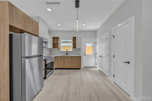 a large kitchen with a refrigerator a sink and white cabinets