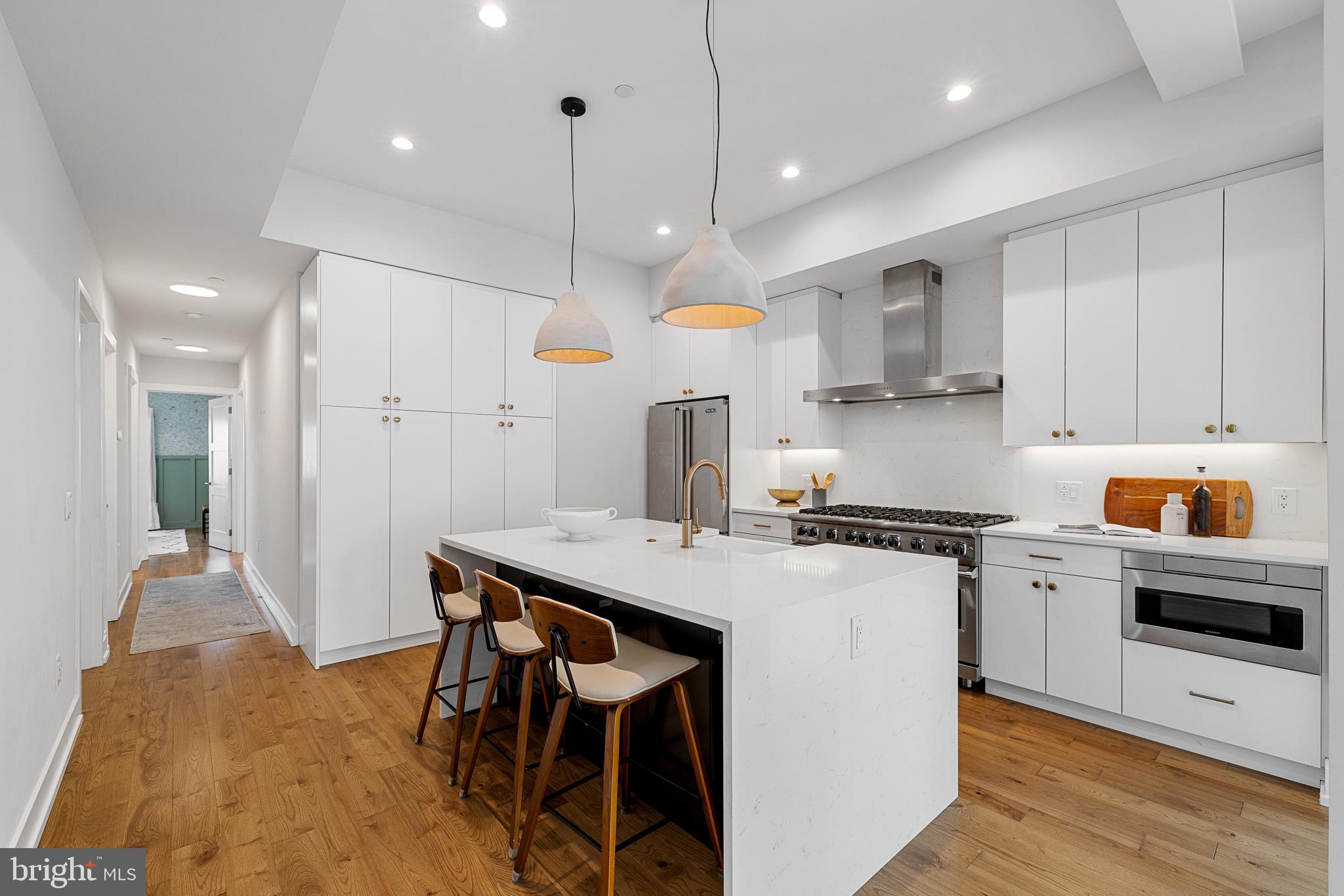 262 South 16th Street, Unit 7 Philadelphia, PA 19102 - Photo 6 of 36 a kitchen with stainless steel appliances a stove a sink a refrigerator and white cabinets with wooden floor