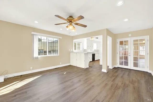 a view of an empty room with a window and wooden floor