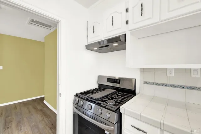 a kitchen with granite countertop a stove and a white cabinets