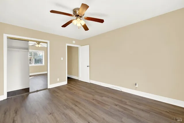 an empty room with wooden floor and ceiling fan