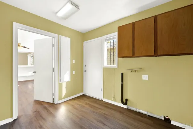 a view of an empty room with wooden floor and a window
