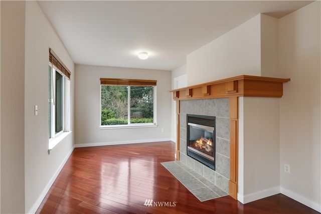 a view of an empty room with wooden floor fireplace and a window