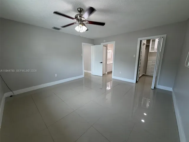 an empty room with windows and fan