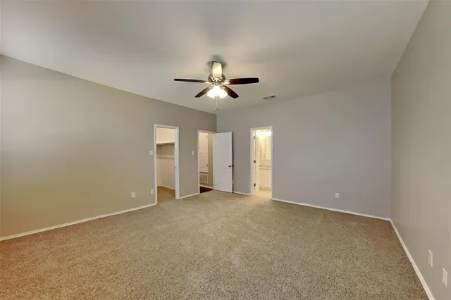 an empty room with chandelier fan and windows