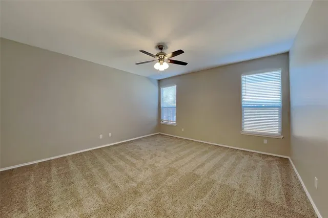an empty room with ceiling fan and window
