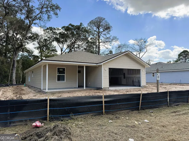 a view of a white house with a small yard and potted plants