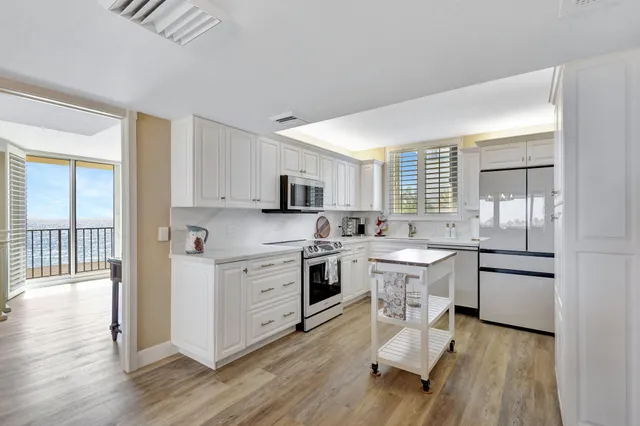 a open kitchen with white cabinets and white appliances