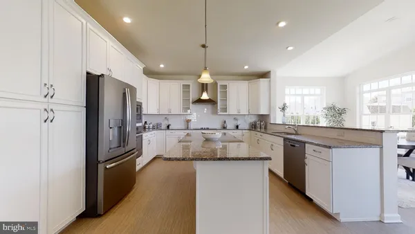 a kitchen with kitchen island granite countertop a refrigerator stove top oven and sink