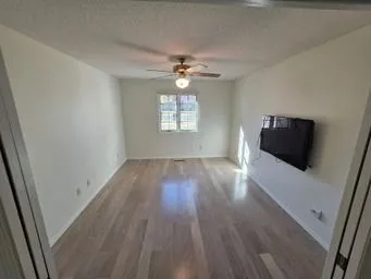 an empty room with wooden floor and windows