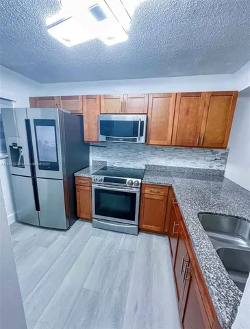 a kitchen with granite countertop a sink cabinets and stainless steel appliances