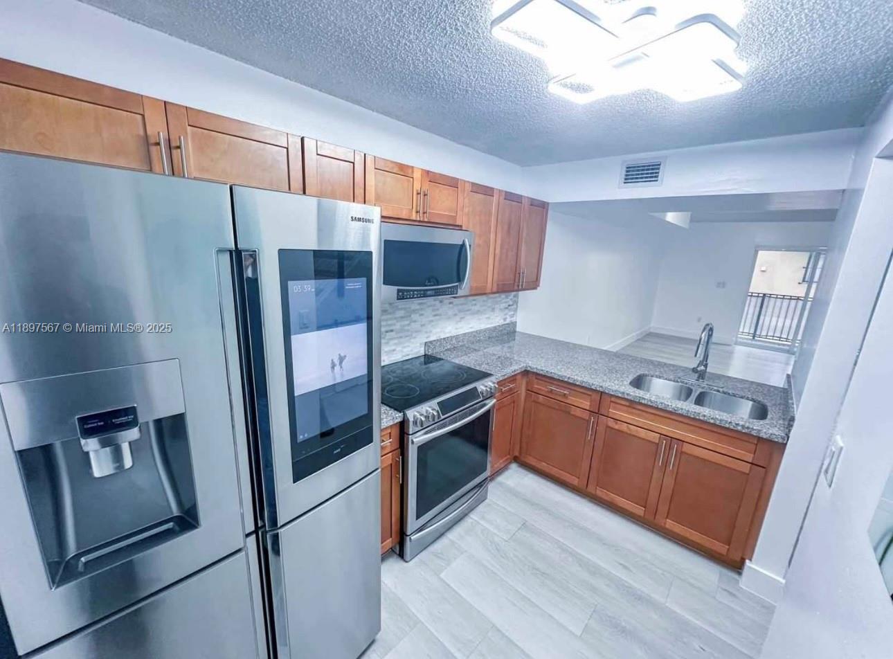 2301 West 60th Street, Unit A211 Hialeah, FL 33016 - Photo 13 of 29 a kitchen with stainless steel appliances granite countertop a refrigerator and a sink