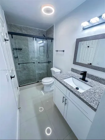 a bathroom with a granite countertop sink a toilet and a shower