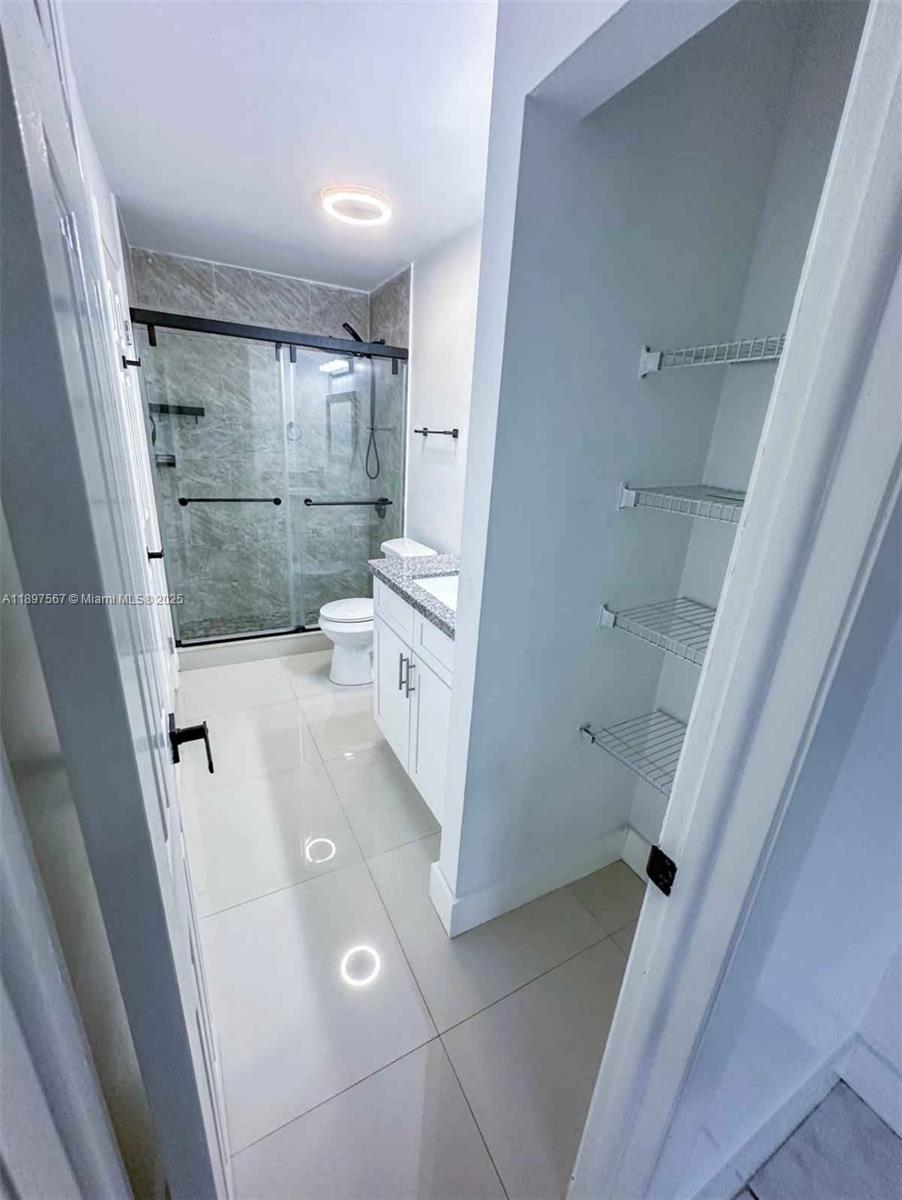 2301 West 60th Street, Unit A211 Hialeah, FL 33016 - Photo 28 of 29 a bathroom with a sink and glass door shower