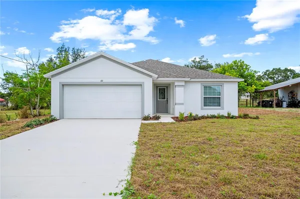 a front view of house with yard and trees in the background