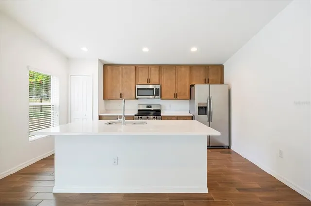 a kitchen with stainless steel appliances a refrigerator a stove a sink dishwasher and a refrigerator with wooden floor