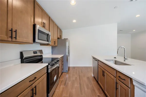 a kitchen with stainless steel appliances a sink dishwasher a stove top oven a refrigerator with wooden floors