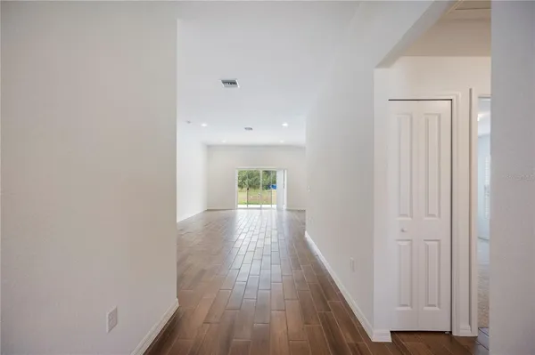 a view of a hallway with wooden floor and a bathroom