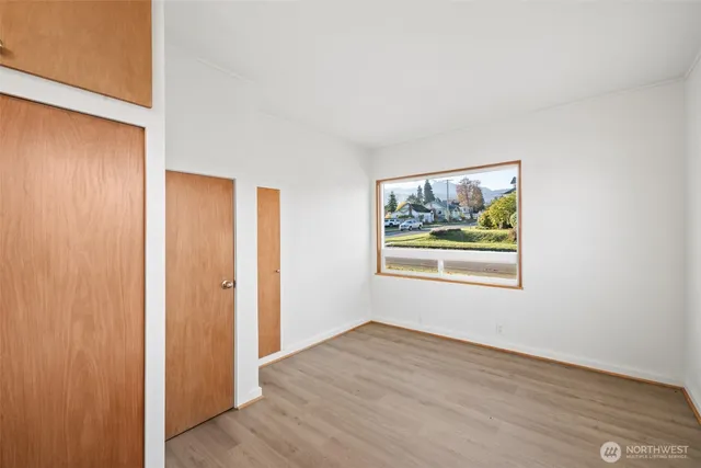 a view of an empty room with window and wooden floor