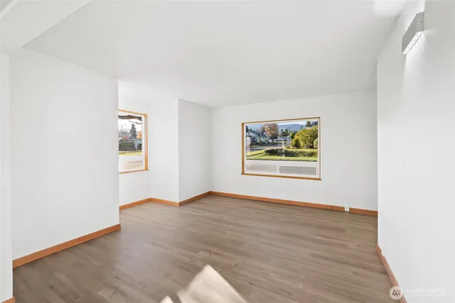 a view of an empty room with window and wooden floor