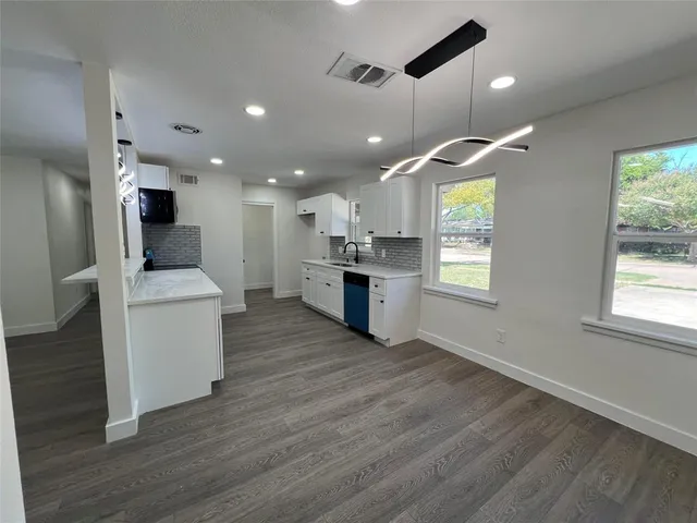 an open kitchen with kitchen island wooden floors and stainless steel appliances