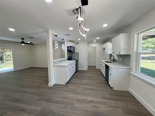 a large kitchen with granite countertop a large counter top a sink stainless steel appliances and cabinets