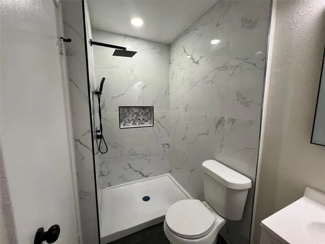 a white toilet sitting next to a bath tub and a shower