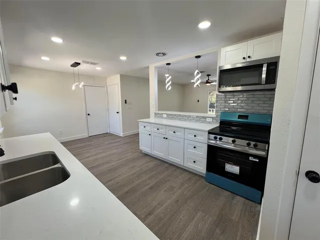 a large kitchen with stainless steel appliances granite countertop a stove and a refrigerator