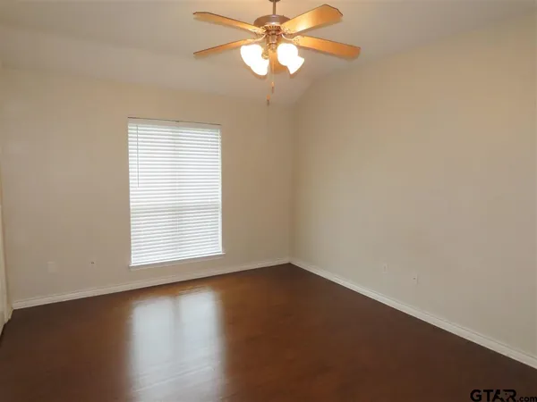an empty room with wooden floor fan and window