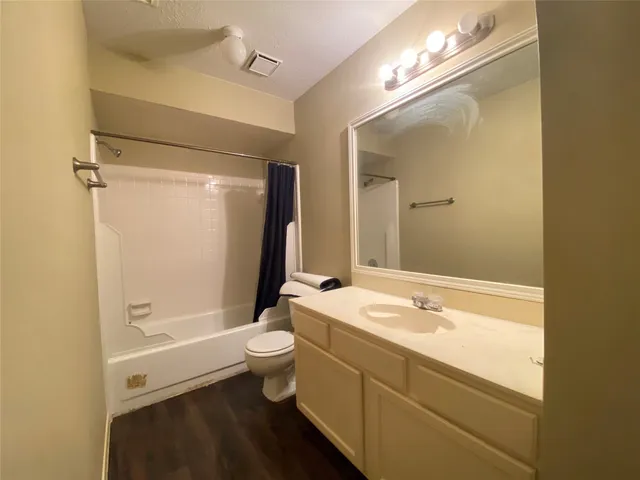 a bathroom with a granite countertop sink a toilet a mirror and shower