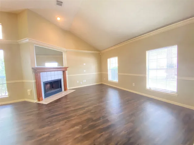 an empty room with wooden floor fireplace and windows