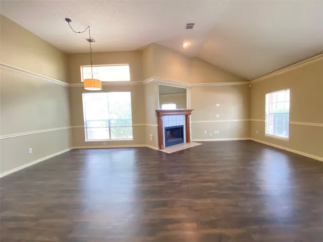 an empty room with wooden floor fireplace and windows