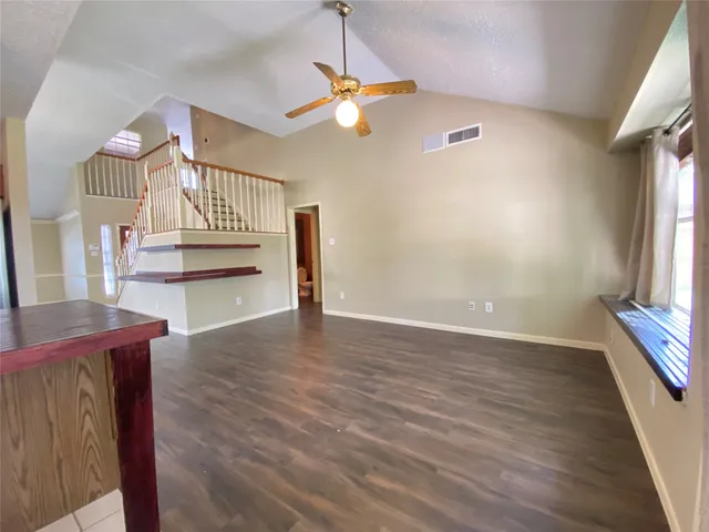 a view of an empty room with a window and wooden floor