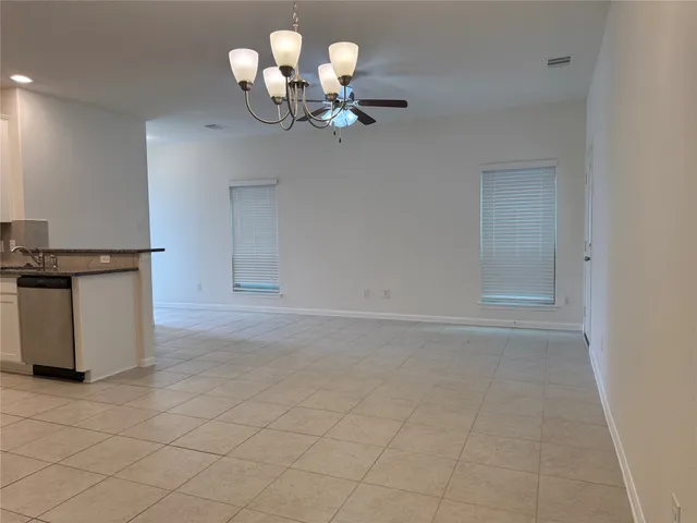 a view of a room with a chandelier fan and kitchen view