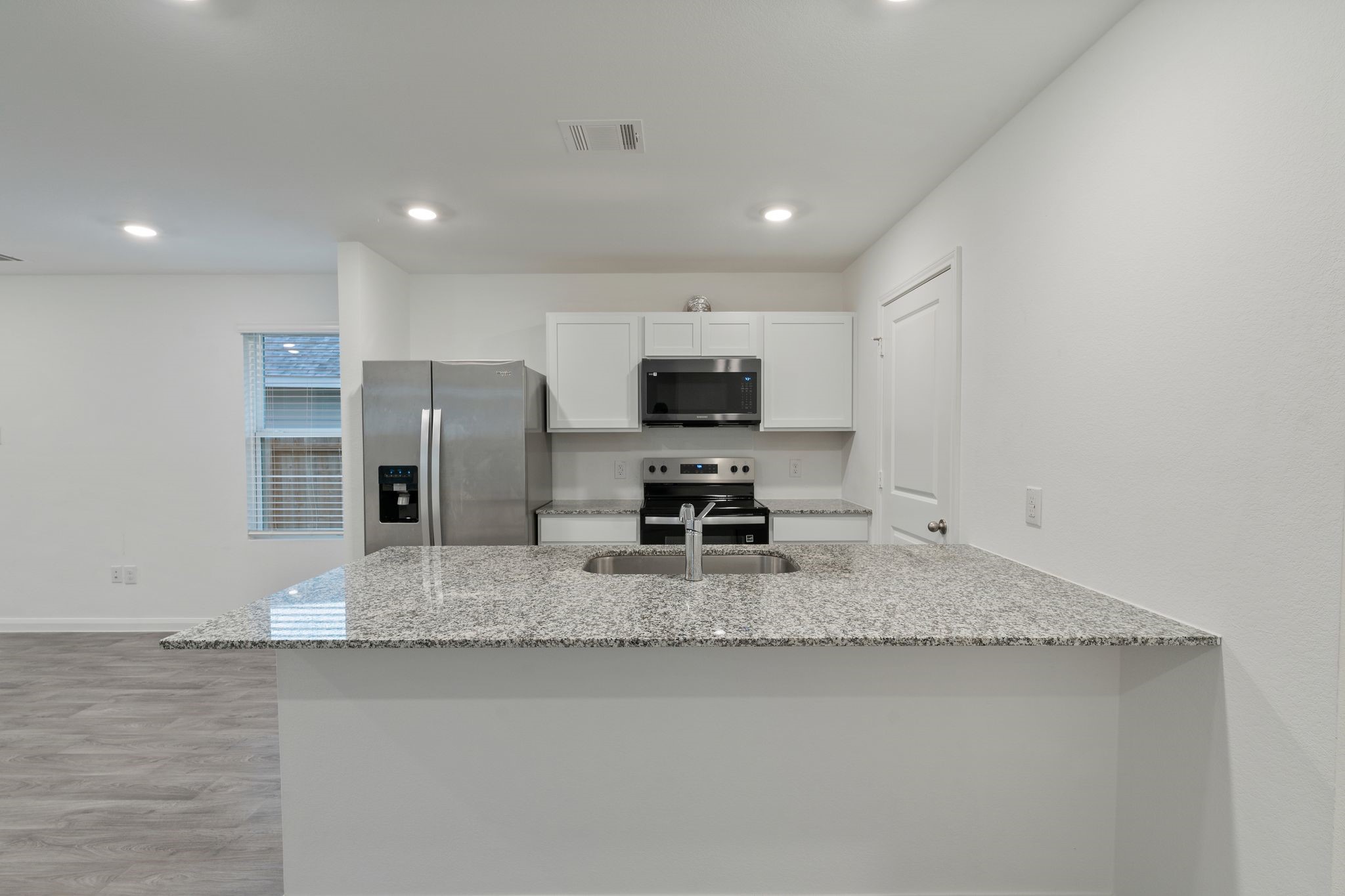12070 William Trails Circle Willis, TX 77378 - Photo 11 of 18 a large kitchen with stainless steel appliances granite countertop a sink a stove a microwave and a refrigerator