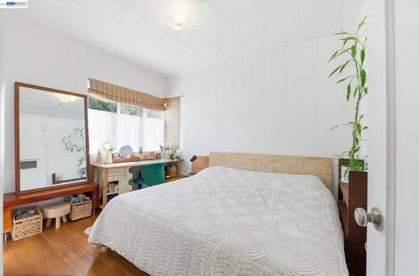 a bedroom with a bed table chair and a potted plant