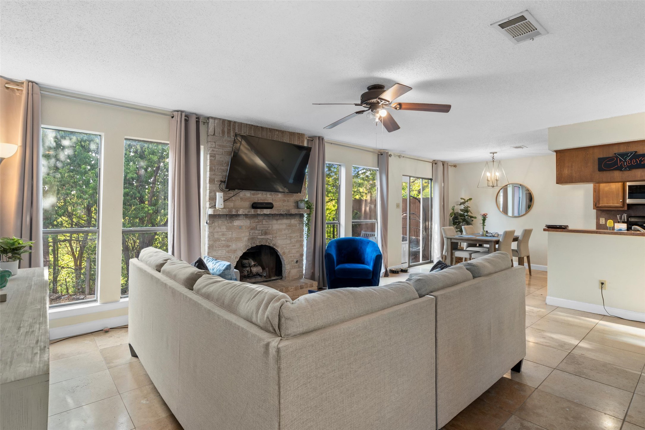 6492 Hart Lane Austin, TX 78731 - Photo 2 of 22 Living area with a brick fireplace, a textured ceiling, ceiling fan, a chandelier, and light tile patterned floors