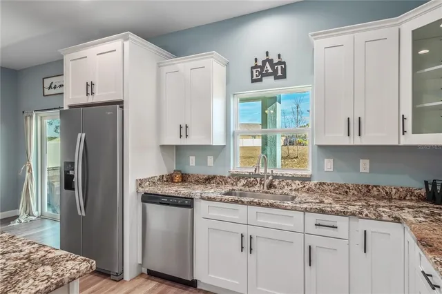 a large kitchen with stainless steel appliances granite countertop a stove a sink and a refrigerator