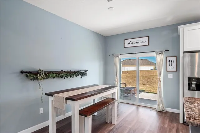 a kitchen with stainless steel appliances granite countertop a stove top oven a sink dishwasher a refrigerator and white cabinets with wooden floor