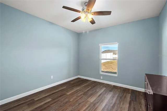 an empty room with wooden floor closet and windows