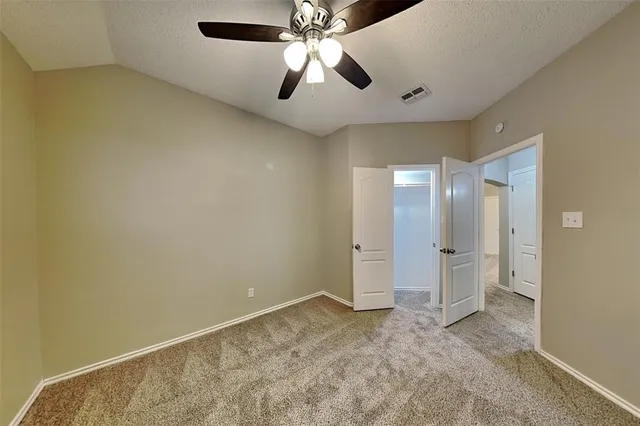an empty room with chandelier fan and closet