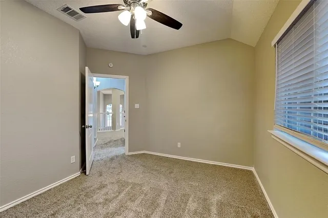 an empty room with a chandelier fan and windows