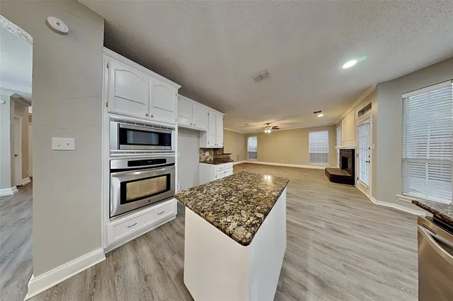 a kitchen with stainless steel appliances kitchen island granite countertop a refrigerator and a stove top oven